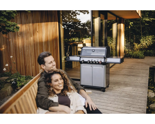 Couple se détendant sur un banc à l'extérieur avec un gril à gaz en arrière-plan.