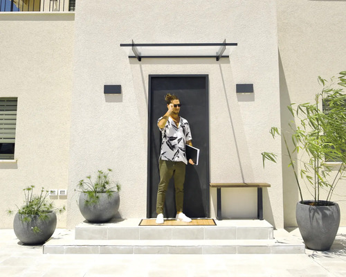 Entrée de maison moderne avec porte foncée, marquise en verre, appliques murales rectangulaires et grands bacs à plantes gris.