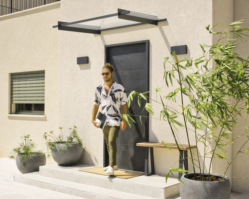 Entrée moderne avec un auvent noir, une porte d'entrée noire minimaliste et des jardinières sur une terrasse claire.