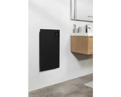 Salle de bains avec un panneau chauffant noir au mur à côté d'un lavabo
