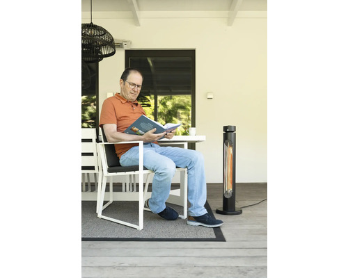 Homme lisant un livre sur une terrasse avec un chauffage de terrasse