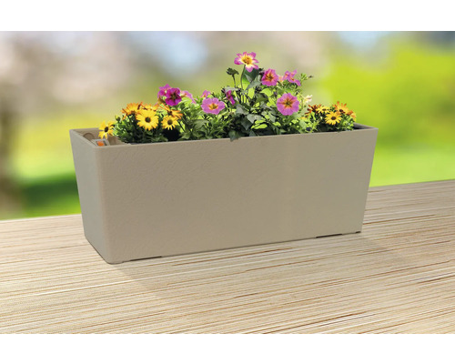 Jardinière beige avec des fleurs jaunes et roses sur une table