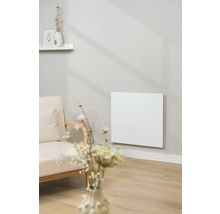 Salon avec un radiateur infrarouge au mur à côté d'un fauteuil