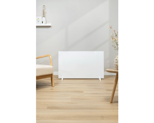 Scène avec un panneau chauffant blanc sur un plancher en bois clair, à côté d'un fauteuil et d'une table d'appoint.