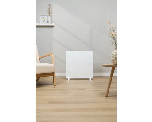 Radiateur blanc dans le salon, à côté d'un fauteuil et d'une table d'appoint.