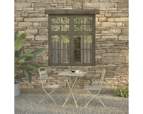 Szene mit Gartentisch, zwei Stühlen, Geschirr und Pflanze vor einer Steinwand