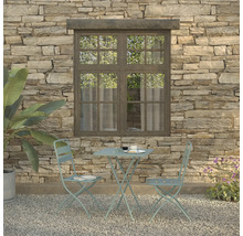 Scène de jardin avec table de bistrot et deux chaises devant un mur en pierre