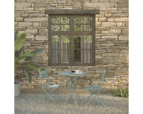 Scène de jardin avec table de bistrot et deux chaises devant un mur en pierre