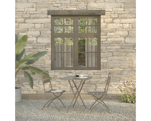 Gartenszene mit Tisch und zwei Stühlen vor einer Steinwand