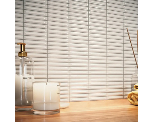 Scène avec des carreaux muraux blancs et allongés, un distributeur de savon, une bougie et une serviette sur une table en bois