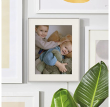 Cadre photo avec passe-partout et photo sur un mur de cadres à côté d'une plante d'intérieur.