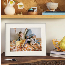 Cadre photo blanc avec passe-partout, posé sur une commode en bois avec décoration.