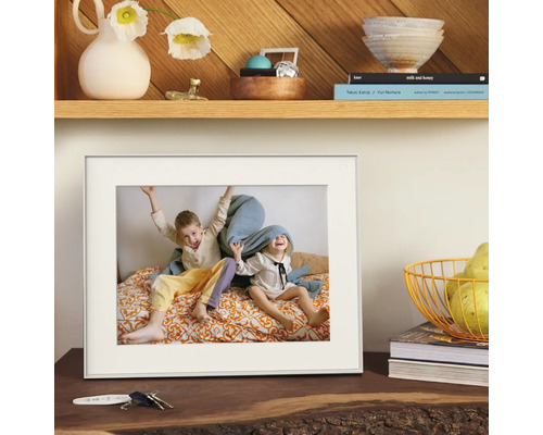 Cadre photo blanc avec passe-partout, posé sur une commode en bois avec décoration.