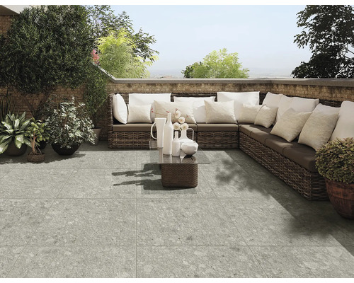 Terrasse avec carrelage gris, canapé en rotin et décoration