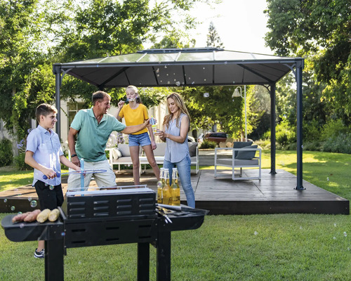 Une famille fait des grillades dans le jardin sous un pavillon et fait des bulles de savon
