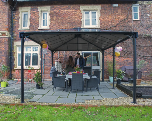 Pavillon de jardin avec famille et table à manger à l'extérieur devant un bâtiment en briques