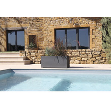 Grauer Pflanzkasten mit Bepflanzung neben einem Pool vor einem Haus