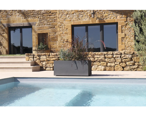 Grauer Pflanzkasten mit Bepflanzung neben einem Pool vor einem Haus