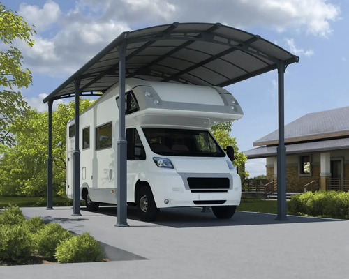 Einzelcarport Palram – Canopia Alpine 6400 359 x 649 cm anthrazit Wohnmobil unter einem Metallcarport auf einem Grundstück.