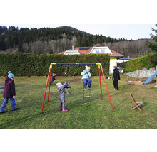 Des enfants jouent sur une balançoire Kettler dans le jardin.