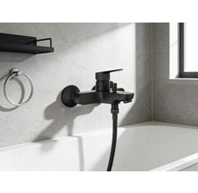 Schwarze Badewannenarmatur mit Handbrause und Badezimmeraccessoires an der Wand über der Badewanne.