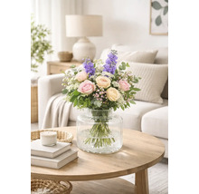 Bouquet de roses et de dauphinelles dans un vase en verre sur une table