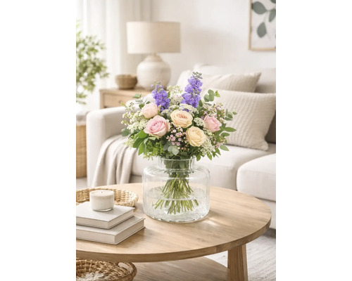 Bouquet de roses et de dauphinelles dans un vase en verre sur une table