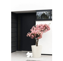 Fleur artificielle décorative avec des fleurs roses dans un pot devant un bâtiment moderne.