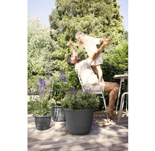 Un père et sa fille jouent dans le jardin à côté de jardinières sur une terrasse en bois