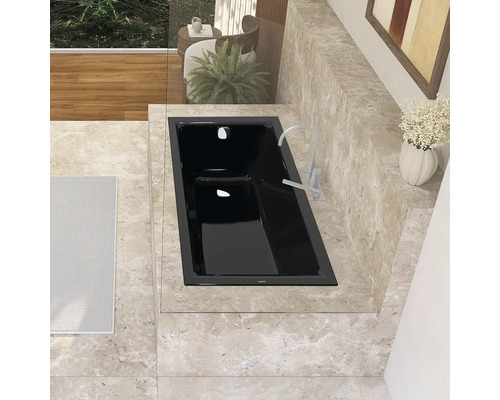 Eingebaute schwarze Badewanne mit Armatur in einem Badezimmer mit Fliesen