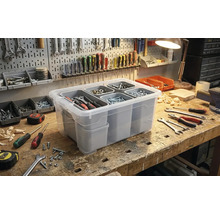 Boîte de rangement transparente avec compartiments pour l'organisation des outils sur un établi.