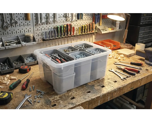 Boîte de rangement transparente avec compartiments pour l'organisation des outils sur un établi.