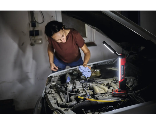 Femme vérifie le niveau d'huile d'une voiture avec une lampe à batterie Einhell