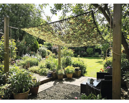 Jardin avec filet de camouflage servant de protection solaire au-dessus d'un coin salon