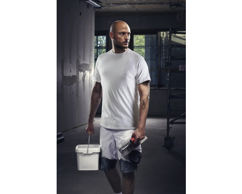 Artisan avec T-shirt, short, seau et truelle sur un chantier