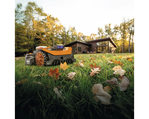 Robot tondeuse à gazon sur une pelouse devant une maison