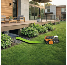 Robot tondeuse à gazon circule sous une terrasse en bois avec un marquage de flèche directionnelle verte.