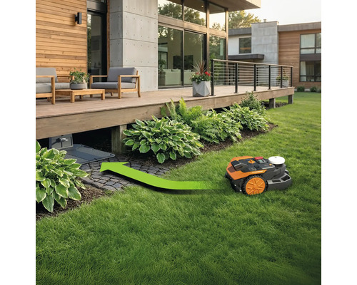 Robot tondeuse à gazon circule sous une terrasse en bois avec un marquage de flèche directionnelle verte.
