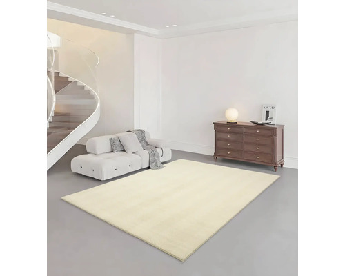 Salon avec tapis beige, canapé, commode et escalier en colimaçon