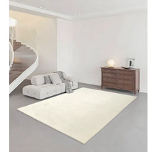Salon lumineux avec tapis clair, canapé, commode et escalier en colimaçon.