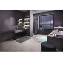 Badezimmer mit Waschtisch, Spiegel, Badewanne, Fenster und Badteppichen