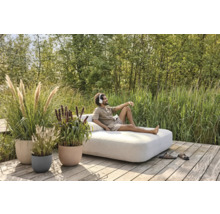 Szene mit Mann, der auf einem Sofa im Freien entspannt, umgeben von Pflanzen in Blumentöpfen auf einer Holzterrasse