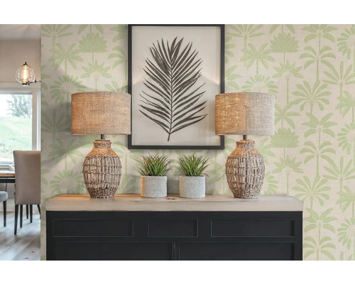 Scène décorative avec deux lampes, des plantes et une image encadrée sur une commode devant un papier peint à motifs de palmiers