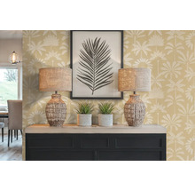 Intérieur décoratif avec deux lampes, deux plantes d'intérieur, une image encadrée et une commode devant un mur à motifs de palmiers.