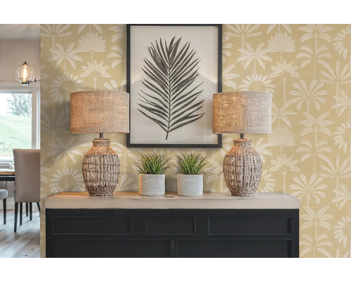 Intérieur décoratif avec deux lampes, deux plantes d'intérieur, une image encadrée et une commode devant un mur à motifs de palmiers.
