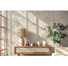 Salon avec papier peint botanique, lampe, décoration et plante sur une armoire en bois.
