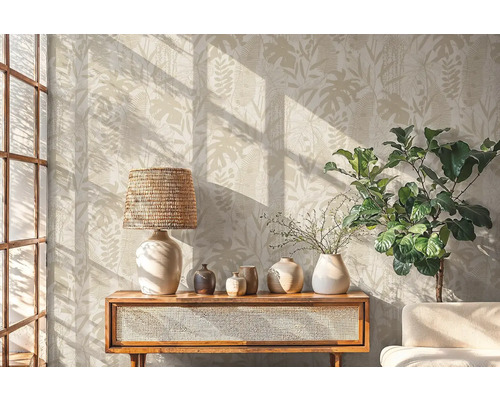 Salon avec papier peint botanique, lampe, décoration et plante sur une armoire en bois.