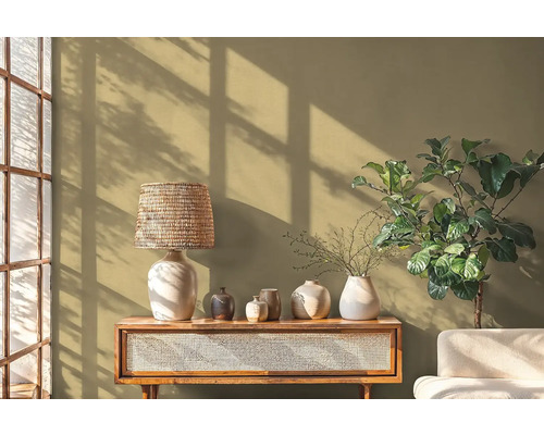 Scène décorative avec lampe de table, vases, table et plante d'intérieur devant un mur