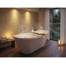 Badezimmer mit freistehender Badewanne, Holzablage, Kerzen und Steinwand