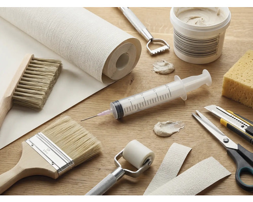 Werkzeuge und Materialien für Tapezierarbeiten auf einem Tisch